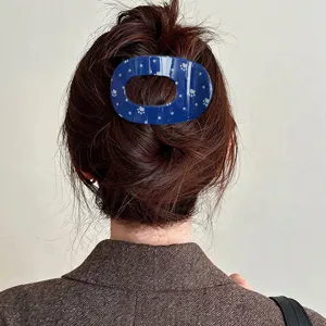 Detailaufnahme einer blauen hohlen ovalen Haarkralle mit süßem Stern- und Pfotenabdruck-Muster.