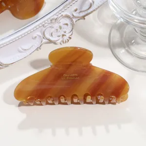 Close-up of tortoiseshell hair claw clip with gold print detail, elegant acetate design.