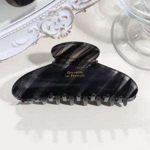 Detail shot of a vintage crescent acetate hair claw clip with black grey marble pattern