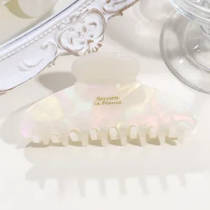 Pearlescent acetate hair claw clip featuring chic gold lettering for elegant hairstyles.