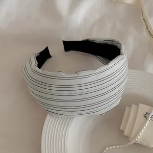 Detail shot of the black and white striped wide fabric headband, elegant tabletop accessory display.
