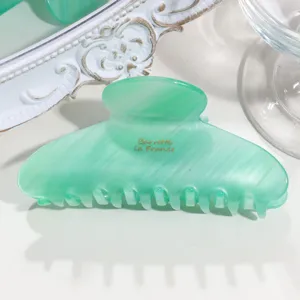 Detailed view of the green translucent acetate hair claw clip with gold text, elegant.