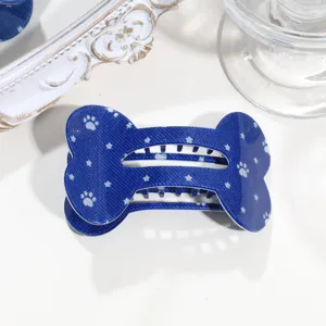 Blaue knochenformige Haarklammer mit weissen Sternen und Pfotenabdruecken, Detailansicht Accessoire.