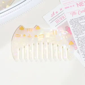 Detail view of cute cat shaped acetate hair comb with pearlescent glossy texture and gold details.