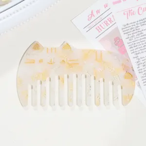 Detail shot of cute cat shaped acetate hair comb with tortoishell texture and golden details.