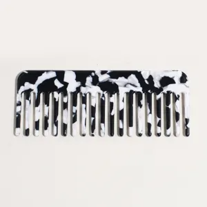 Black and white acetate wide-tooth comb close-up showing smooth marbled texture surface.