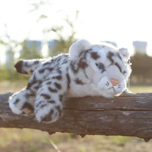 Vista detallada de peluche realista de leopardo de las nieves, animal suave sobre tronco.