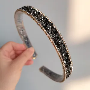 Detailed view of a sparkling black rhinestone headband with gold trim, elegant party hair accessory.