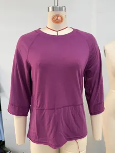 Detail view of a purple women's 3/4 sleeve raglan t-shirt with solid color and spliced hem.