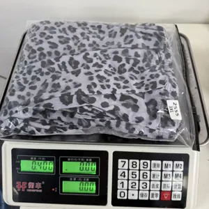 Detail shot of leopard print trousers packaging and weighing, showing product size and quality info.