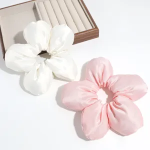 Nahaufnahme süßer Blumen-Haargummis aus Satin in Weiß und Rosa, elegantes Detail.