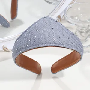 Detail shot of a grey crown-shaped rhinestone fabric headband with brown leather lining.