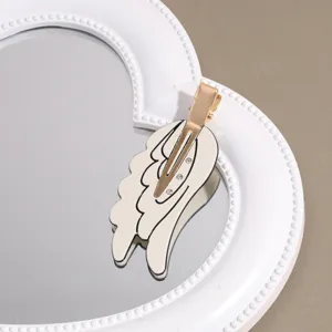 Close-up of sweet angel wing hairpin featuring rhinestone details and golden clip structure.