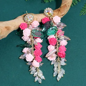Detailed view of long floral tassel earrings featuring pink resin roses and sparkling crystals.
