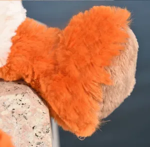 Plush toy detail closeup showing soft orange and white fluffy fur texture on stone ledge.