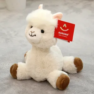 Close-up of cute white plush alpaca toy with brown hooves sitting softly on grey mat.