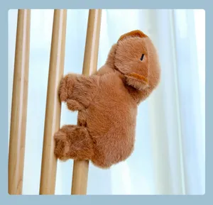 Close-up detail of the cute brown capybara plush slap bracelet clinging on wooden rod.