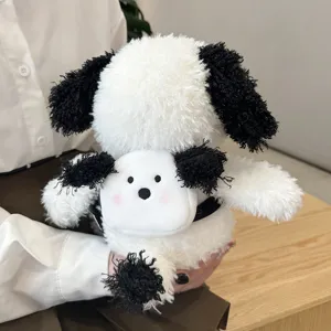 Cute plush dog toy detail showing soft white fur and black floppy ears held in hands.