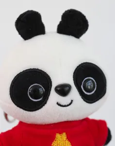 Close-up shot showing the soft black and white texture of the cute panda plush keychain detail.