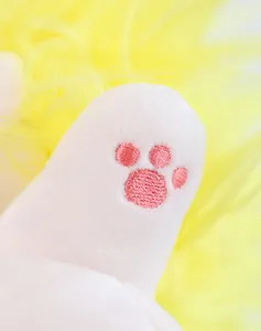 Plueschpuppen Detailaufnahme mit einer niedlich gestickten rosa Pfote auf weissem Stoff.
