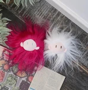 Detailaufnahme von flauschigen Plueschpuppenkopf Schluesselanhaenger mit langen Haaren in rosa und weiss.