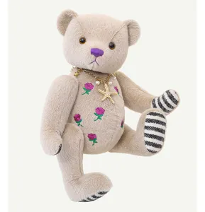 Orsetto di peluche articolato con rose ricamate e una collana di stelle elegante.