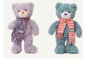 Close-up van schattige pluche teddybeer met gekleurde gebreide sjaal, zacht speelgoed.