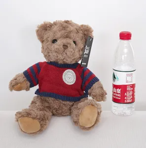 Detailed view of cute brown teddy bear plush toy wearing red and blue knitted sweater doll.