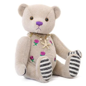 Simpatico orsacchiotto di peluche con ricamo di rose e collana con stella marina.