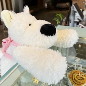 Detailansicht des flauschigen weißen Highland-Hund-Plüschtiers mit rosa Rucksack, Kuschelgeschenk.