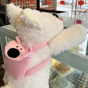 Nahaufnahme des flauschigen weißen Plüschhundspielzeugs mit einem süßen rosa Strickrucksack.