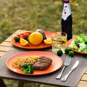Assiette plate en mélamine orange corail, vaisselle ronde mate pour steak, pâtes et salades.