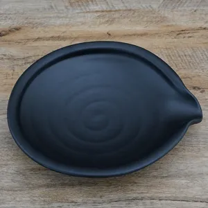 Assiette plate en melamine noire avec bec verseur irregulier et texture relief cuisine.