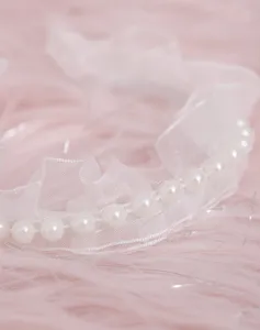Dettaglio di finiture in pizzo bianco con perle per abiti da bambola DIY, grazioso.