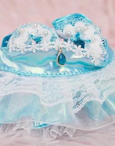 Primo piano dettagliato dell'abito blu da bambola con pizzo, perle e ciondolo.