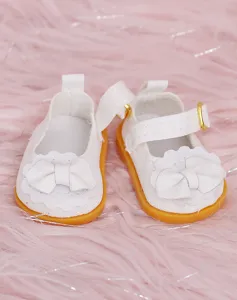 Primo piano dettagliato di scarpe da bambola bianche con fiocco carino e suola gialla per 20cm.
