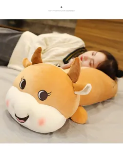 Dettaglio del cuscino lungo in peluche a forma di mucca sul letto con tessuto morbido.