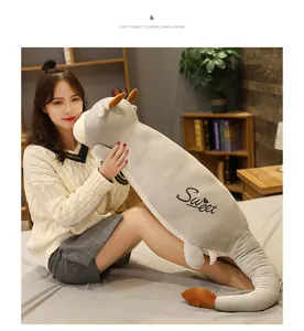 Dettaglio peluche mucca con coda lunga, morbido cuscino grigio per relax a letto.