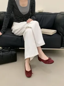 Detailansicht von damen bordeauxroten flachen ballettschuhen mit einer süßen schleife.