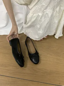Vista dettagliata di scarpe basse nere con grazioso fiocco e punta tonda elegante.