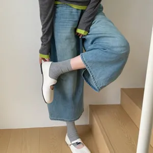Detailed shot of trendy split toe flat shoes paired with cozy socks and wide jeans.