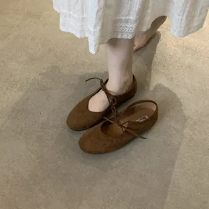 Detailed view of women's brown suede lace-up bow flat shoes, vintage Mary Jane style.