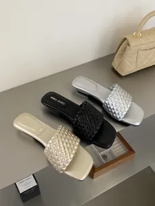Detalle en primer plano de sandalias mules trenzadas elegantes con punta cuadrada.