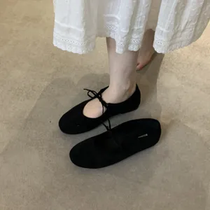 Black genuine leather lace-up bow ballet flat shoes detail shot showing soft sole and straps.