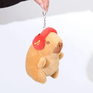 Capybara plush keychain detail showing cute brown animal doll wearing red music headphone charm.