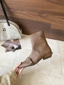 Nahaufnahme von braunen Stiefeletten mit spitzer Kappe und eleganter Metallschließe.