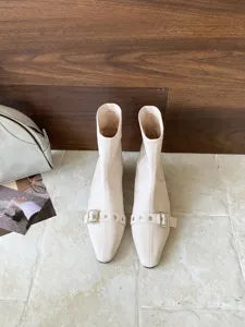 Beige spitz zulaufende Stiefeletten mit eleganter Metallschnalle und bequemem niedrigen Blockabsatz.