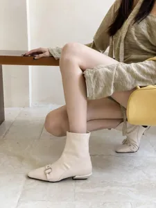 Detailaufnahme beige spitzer Stiefeletten mit niedrigem Blockabsatz und Metallschließe.