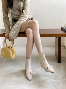 Detailaufnahme stylischer beige spitzer Boots mit niedrigem Blockabsatz und Schnalle.