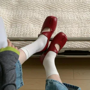 Close-up detail of red split-toe flat mary jane shoes with white socks, soft sole daily look.